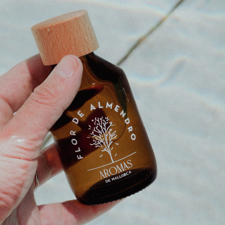 Fragancia artesanal Flor de Almendro — detalle del difusor Mikado en ambiente hogareño mediterráneo